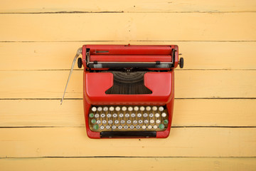 Vintage red typewriter on the yellow wooden table
