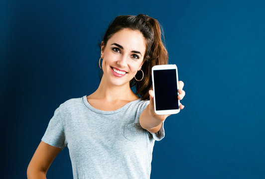 Young Woman Using Her Phone On Dark Blue Background