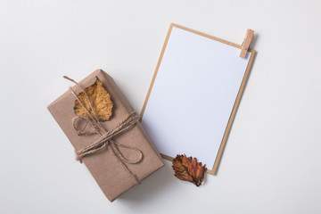 From above autumn composition made with paper card mock up / invitation and craft gift box with yellow leaf on white. Top view. Flat lay.