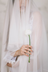 Obraz premium Beautiful girl bride holding a white flower, Ranunculus, close-up