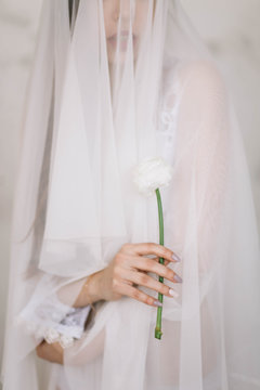 Beautiful girl bride holding a white flower, Ranunculus, close-up