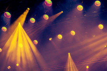 Lighting equipment on the stage of the theatre during the performance. The light rays from the spotlight through the smoke. Yellow rays of light.
