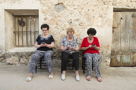 Three women of age advanced with smartphone