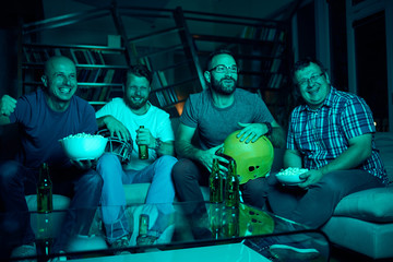 Four men watching american football game on television