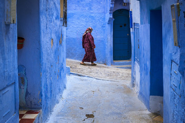 Chefchaouen, Morocco - April 10, 2016: Moroccan woman walking in a narrow street in the town of...