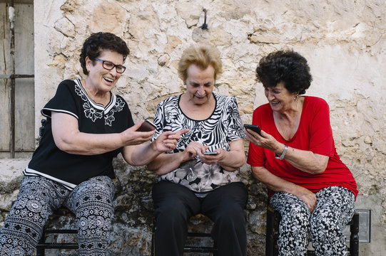 Three women of age advanced with smartphone