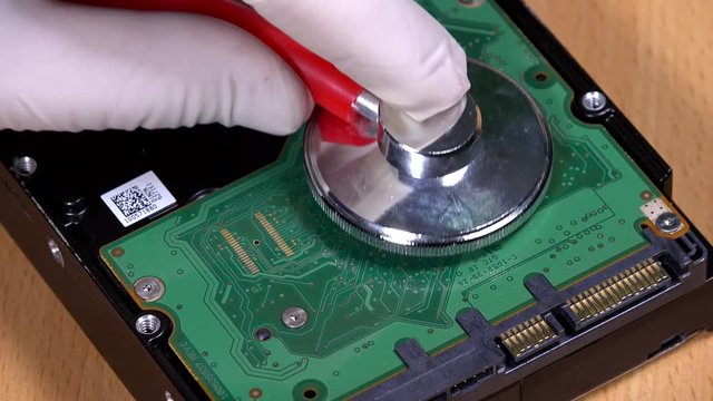 Hand with stethoscope on computer hard drive HDD. Data recovery concept