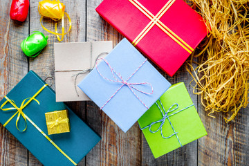 Colored gift boxes on wooden background with ribbon and straw