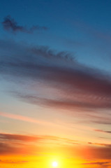 Fototapeta na wymiar A warm dawn with sun and pinnate multicolored clouds.