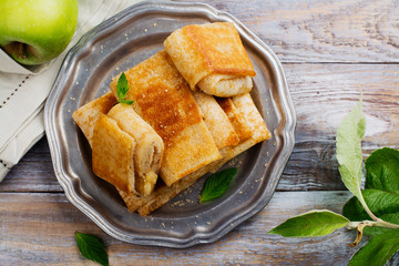 Crepes with apples, lemon and cinnamon on wooden table. Space for text