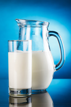 Milk in a jar and a glass and cookies on blue background