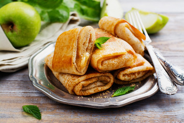 Crepes with apples, lemon and cinnamon on wooden table. Space for text