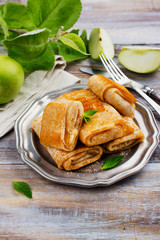 Crepes with apples, lemon and cinnamon on wooden table. Space for text