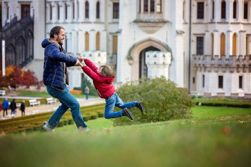 Father, spinning in circles his little son on a lawn in front of the Hluboka castle