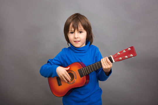 Preschool child, playing little guitar, isolated image