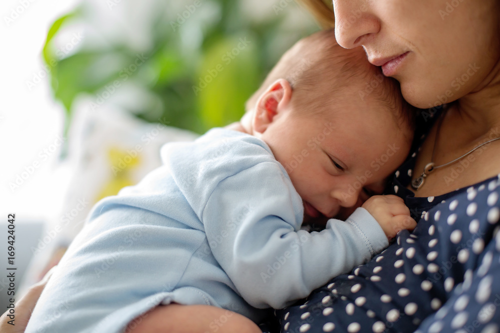 Poster Young mother, holding tenderly her newborn baby boy