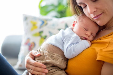 Young mother, holding tenderly her newborn baby boy
