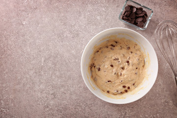 Bowl with raw dough and chocolate chips on kitchen table