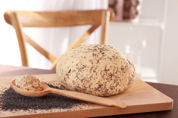 Raw dough with poppy seeds and spoon on wooden board