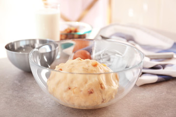 Bowl with raw dough and raisins on kitchen table