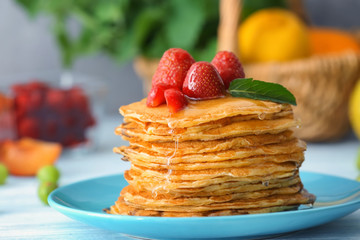 Delicious pancakes with honey and strawberry on table