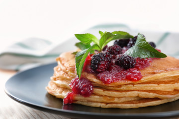 Plate with delicious pancakes on table