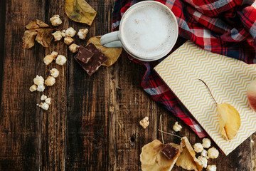 Hot cocoa (coffee) with popcorn, apple, cakes, leaves on the old wooden boards. Cozy, autumn concept
