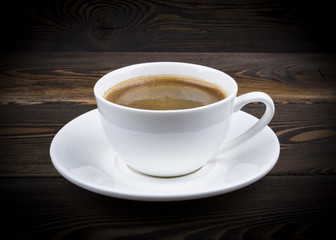 Obraz premium Overhead view of a freshly brewed mug of espresso coffee on rustic wooden background with woodgrain texture. Coffee break style, concept