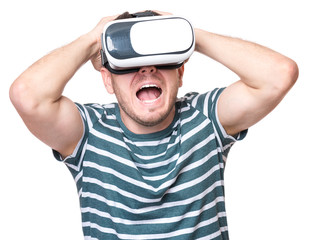 Naklejka premium Young man with a frightened pose with virtual reality goggles watching movies or playing video games, isolated on white background. Man is looking scared. People experiencing 3D gadget technology.