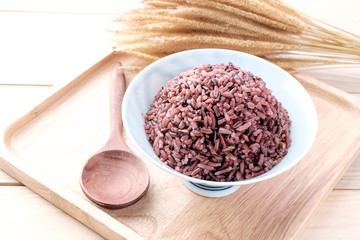 Brown Rice with wooden spoon on wooden background