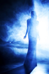 Silhouette of the beautiful girl in blue theatrical. fog.