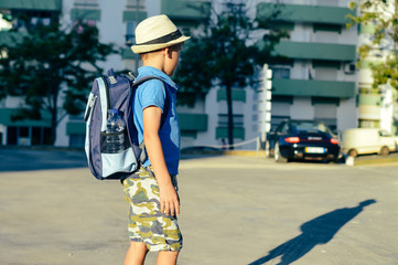 Back view of adorable little boy holding backpack go to school. Busy lifestyle outdoors journey background