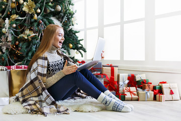 Surprised woman online on laptop at christmas interior
