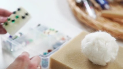 Stages and technique of dry felting of wool: in the hands of the needlewoman a piece of white felt, she inserts into a needle to tighten the wool and give the desired shape.