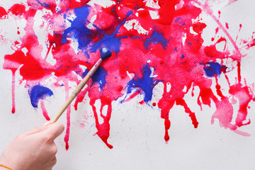 Brush and paint jar in hands. Artist creating watercolor painting