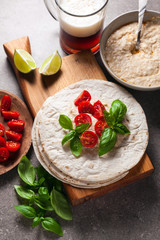 Home tortilla with hummus of white beans and beer on a gray stone table. Italian, Mediterranean style. With tomatoes and basil . dark beer