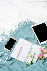 Vertical Flat lay tablet, phone, cup of coffee and flowers on white blanket with turquoise plaid