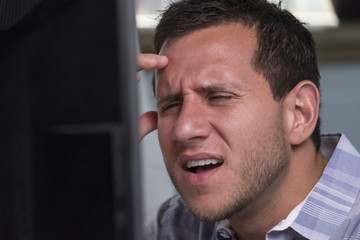 Man looking angry while looking at his computer screen