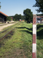 Small train station on narrow-gauge. Sunshine weather, village train stop. Railroad tracks, railway...