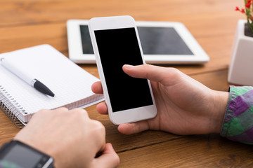 Man using smartphone at workplace, close up