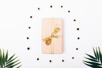 Top view of a box with a gift and a gold ribbon and palm branches
