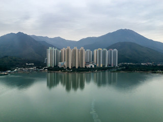 Tall building apartments in Hong Kong island showing density of residence in diversity with natural background of sea, mountain peak and forest from high view