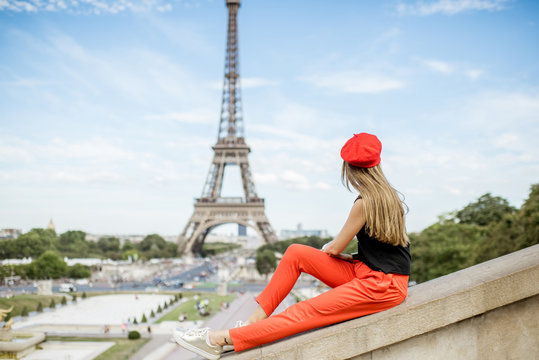 Young woman in red cap and pants enjoying great view on the Eiffel tower in Paris