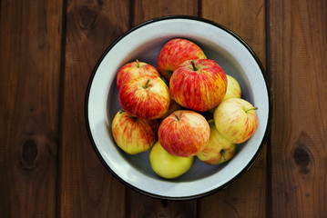 Seasonal garden red apples in metal bowl on wooden background. Fresh harvest. The view from the top