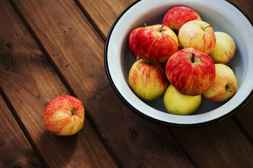 Seasonal garden red apples in metal bowl on wooden background. Fresh harvest