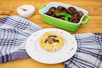 Tartlets with champignons on wooden background