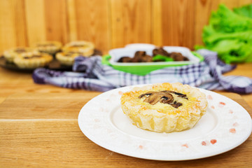 Tartlets with champignons on wooden background