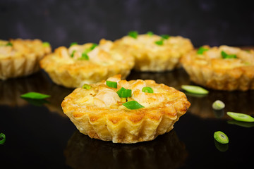Tartlets with chicken and zucchini on dark background