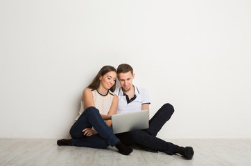 Cheerful couple using laptop at home, copy space