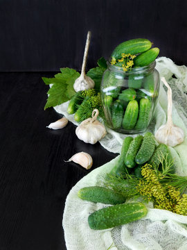 Cucumbers and ingredients for conservation are scattered on a dark table